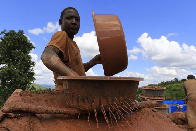 A boy washes stone dust in search of gold nuggets at an open-pit gold mine in Lukingi village in Mubende district